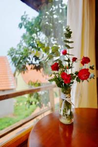 un vase rempli de roses rouges assis sur une table dans l'établissement Lim Village - Nam Ban, à Namban