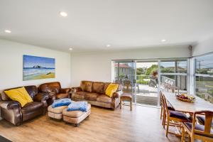 ein Wohnzimmer mit Ledermöbeln und einem Tisch in der Unterkunft Coastal Haven - Waimarama Holiday Home in Waimarama