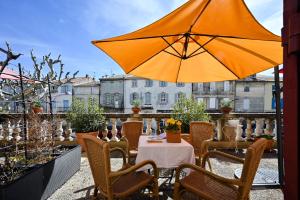 eine Terrasse mit einem Tisch und einem Sonnenschirm in der Unterkunft Hotel Des Artistes in Tarascon
