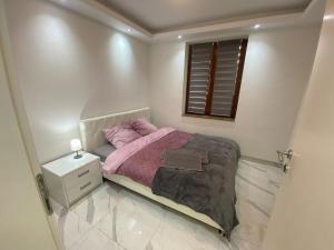 a small bedroom with a pink bed and a window at Apartman Stivi Deluxs 2 in Vrnjačka Banja