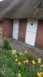 a brick house with two white doors and flowers at FRIESENGLÜCK in Syltnähe! in Braderup