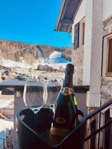 two glasses and a bottle of wine on a balcony at Sasso Nero in Chiesa in Valmalenco