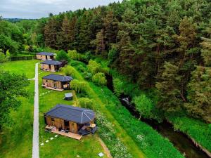 a group of cottages in a field next to a river at Riverside Cabins in Shrewsbury