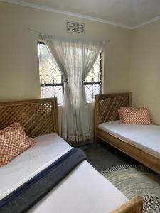 twee bedden in een kamer met een raam bij Wonders Hostel in Arusha