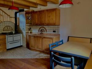 una cocina con armarios de madera, mesa y fregadero en Baita Oasi Nembia, en San Lorenzo in Banale