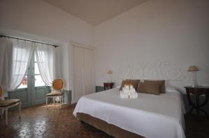 a bedroom with a large white bed and two chairs at La Salina Hotel Borgo Di Mare in Lingua