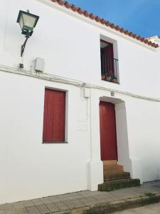 um edifício branco com portas vermelhas e uma luz de rua em Casa Mora em Encinasola