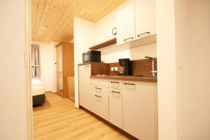uma cozinha com armários brancos e piso em madeira em Almliesl MAIS-700 em Maishofen