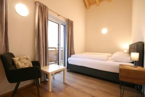um quarto com uma cama, uma janela e uma cadeira em Almliesl MAIS-700 em Maishofen