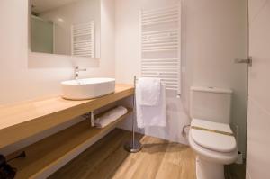 bagno bianco con lavandino e servizi igienici di Apartamentos Lucio Rodinso 