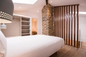 een slaapkamer met een wit bed en een bakstenen muur bij Apartamentos Lucio Rodinso 