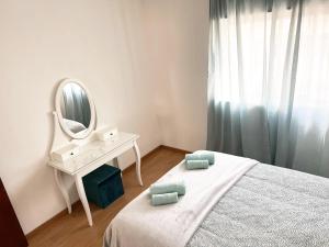 a white bedroom with a bed and a mirror at Apartamento da Fonte in Figueira da Foz
