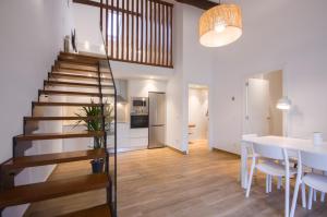 una scala in un soggiorno con tavolo e cucina di Apartamentos Lucio Rodinso 