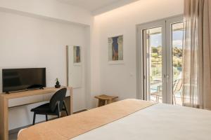 a bedroom with a bed and a desk and a television at Summertime Villas in Argostoli