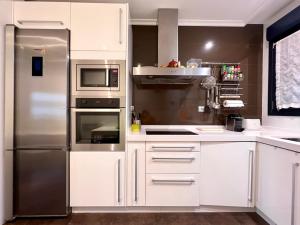 uma cozinha com armários brancos e um frigorífico de aço inoxidável em Housingleón - Centro Colón em León