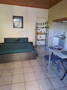 Cet appartement comprend une chambre avec un lit, une table et une cuisine. dans l'établissement Gîte "LE LAURUS" aux Magnolias, à Aubenas