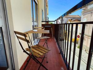 un balcón con una mesa de madera y sillas. en Apartamento da Fonte en Figueira da Foz