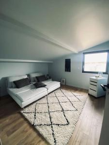 a bedroom with a white bed and a rug at Maison de ville avec un charme atypique in Pontarlier