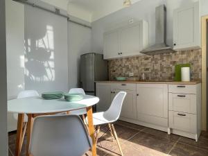 a kitchen with white cabinets and a table and chairs at Skyline Apartments in Rīga