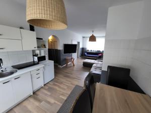 a kitchen and living room with white cabinets and a table at Apartament Julia Łeba Kwiatowa in Łeba