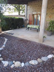 a patio with a bunch of rocks and a bench at Gîte 5 "LE LAURUS" aux Magnolias in Aubenas