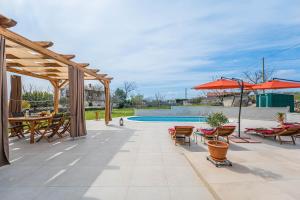 a patio with a table and chairs and a pool at Ferienhaus/HolidayHouse Smokvica **** in Rakalj in Rakalj
