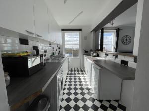 a kitchen with a black and white checkered floor at Coastal Comfort, Seaside Flat in Margate