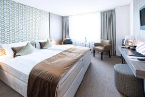 ein Hotelzimmer mit einem großen Bett und einem Schreibtisch in der Unterkunft Bernstein Salzlandcenter in Staßfurt + 17 Fotos