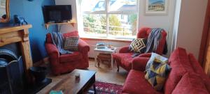 a living room with two red couches and a tv at The Hill House Meenaleck with Sunrise views in Crolly