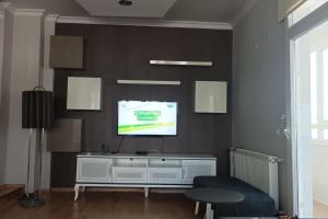 3 rooms and living room, centrally located, large apartment في Bayrakli: غرفة معيشة مع تلفزيون بشاشة مسطحة على جدار