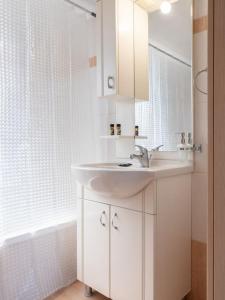Baño blanco con lavabo y espejo en Apartment Santa Marina 6, en Asgourou