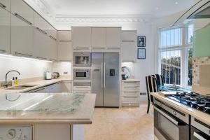 a kitchen with white cabinets and a stainless steel refrigerator at Finest Retreats - Elm Point House in London