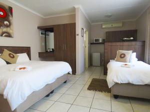 a hotel room with two beds and a kitchen at Andante Guesthouse Klerksdorp in Klerksdorp