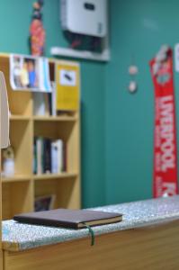 un ordenador portátil sentado en la parte superior de un mostrador junto a un estante de libros en Albergue Rojo Plata, en Torremegía