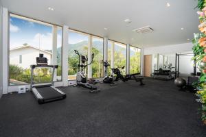 a gym with treadmills and ellipticals in a room with windows at Himmapana Villas - Hills in Kamala Beach