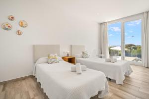 Cette chambre blanche dispose de deux lits et d'une fenêtre. dans l'établissement Villa Sunrise, à Son Bou 23 autres photos