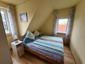 a small bedroom with a bed and two windows at Ferienwohnung Leuchtturm am Sandstrand in Norden