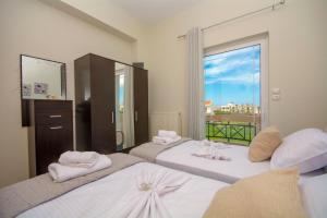 two beds in a room with a large window at Jasmine House Kissamos in Kissamos