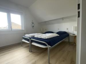 1 dormitorio con cama con sábanas azules y ventana en Esdoornstraat 4 en Cadzand