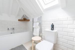 a white bathroom with a toilet and a bath tub at Simple Coastal Luxury near Southwold sleeps 10 in Southwold +21 photos