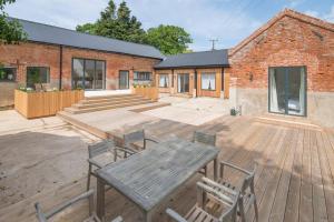 a patio with a wooden table and chairs and a brick building at Simple Coastal Luxury near Southwold sleeps 10 in Southwold