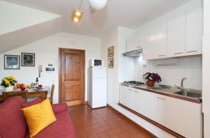 een keuken met witte kasten en een rode bank bij Perla in Spello