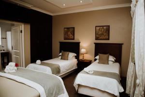 a hotel room with two beds with white sheets at Alveston Manor Hotel in Middelburg