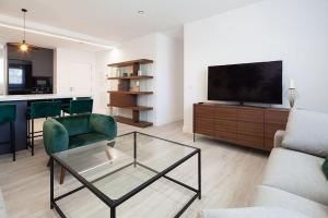 sala de estar con TV, sofá y mesa en Stunning apartment in Nervion with parking en Sevilla