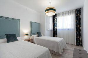 Cette chambre blanche dispose de deux lits et d'une fenêtre. dans l'établissement Stunning apartment in Nervion with parking, à Séville