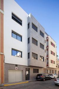 un edificio blanco alto con coches estacionados en un estacionamiento en Stunning apartment in Nervion with parking en Sevilla