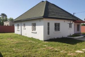 uma pequena casa branca com um telhado preto em House in brufut near the sea / tanji bird reserve em Brufut