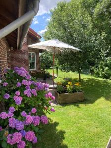 a patio with flowers and an umbrella in a yard at Ferienwohnung Margrit in Detern