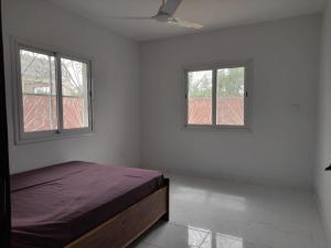 um quarto branco com uma cama e 2 janelas em House in brufut near the sea / tanji bird reserve em Brufut