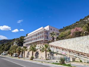 a building on the side of a hill with palm trees at La Vela in Finale Ligure